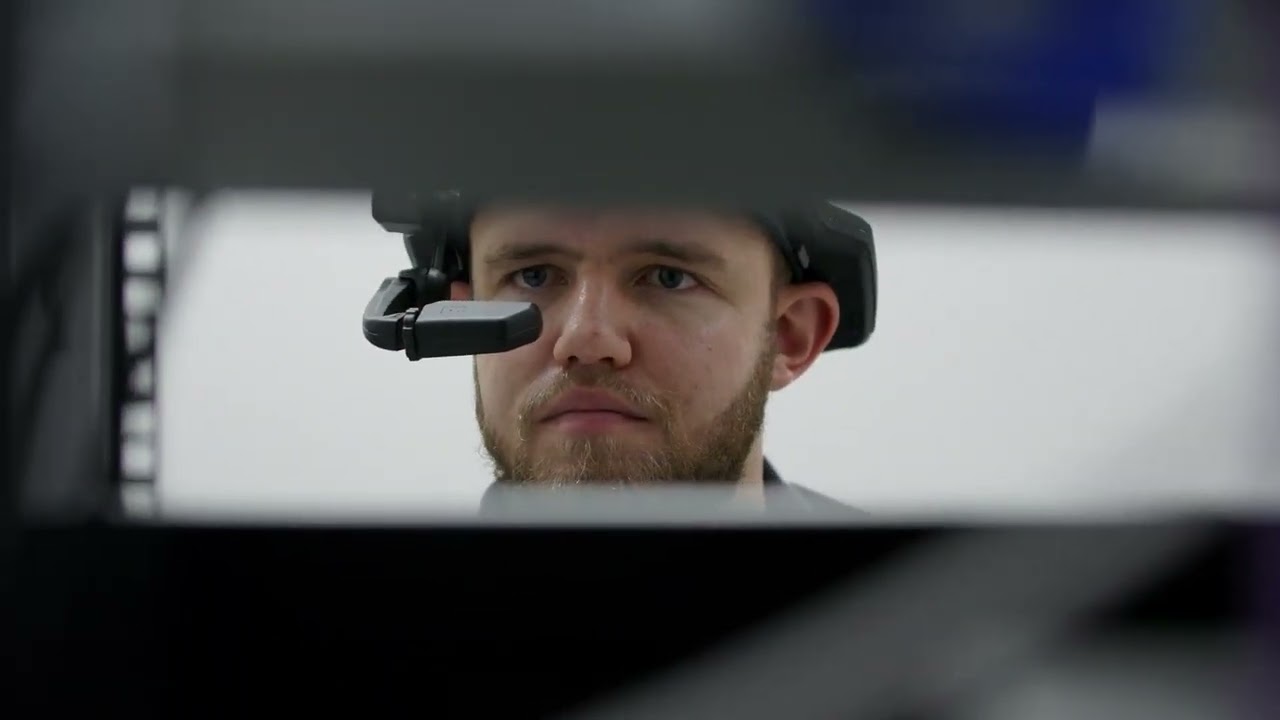 A Pulse Data Centre technician wearing a RealWear device, viewed through server rack framing