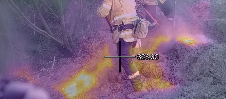 Thermal camera view of firefighters at a real wildfire in Canterbury, showing multiple hot spots glowing in the surrounding ground